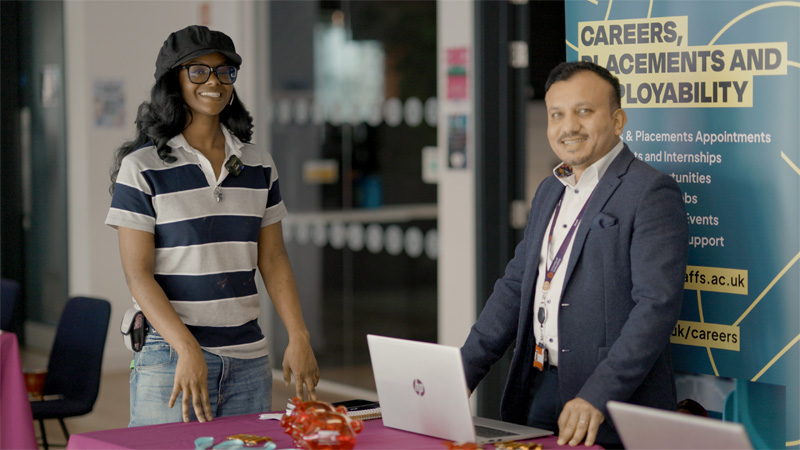 A female student is chatting to a careers advisor at a stand
