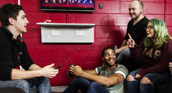 A group of casually dressed students are sitting in a lounge area socialising