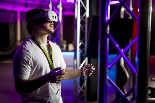 A male wearing a white tshirt and a VR headset is using the VR equipment in the open Games studio