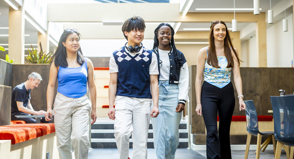 A group of young students are smiling and walking inside the Stafford open leisure space