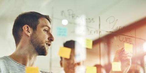 Group of people working with post-it notes photographed through glass wall.