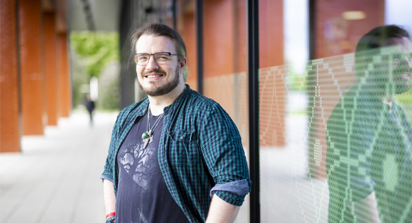 A male wearing casual clothing is standing outside the Catalyst building, smiling