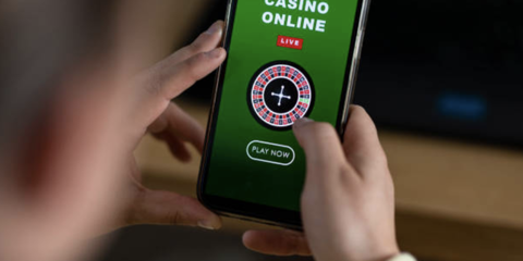 Hands holding a mobile phone with an online casino game on the screen 