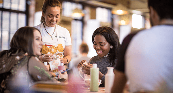 A group of students are painting ceramics and smiling